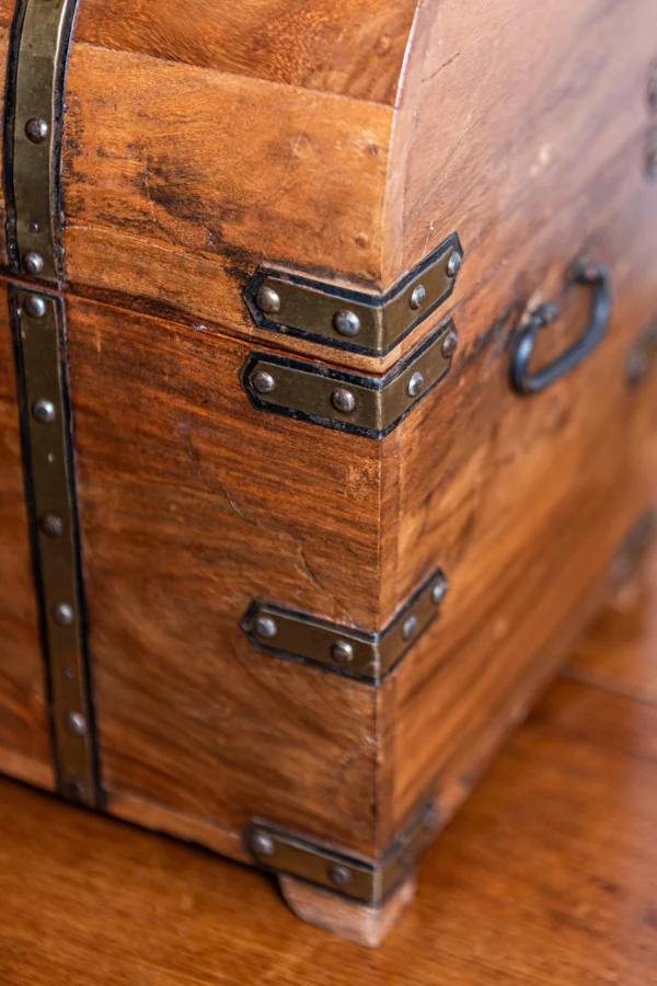 Reference photograph showing the chest's wrapping corner braces, rivets, wood grain and iron handle